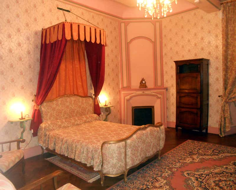 Lit à baldaquin et cheminée de la chambre Madame de Maintenon au Château de Malvirade